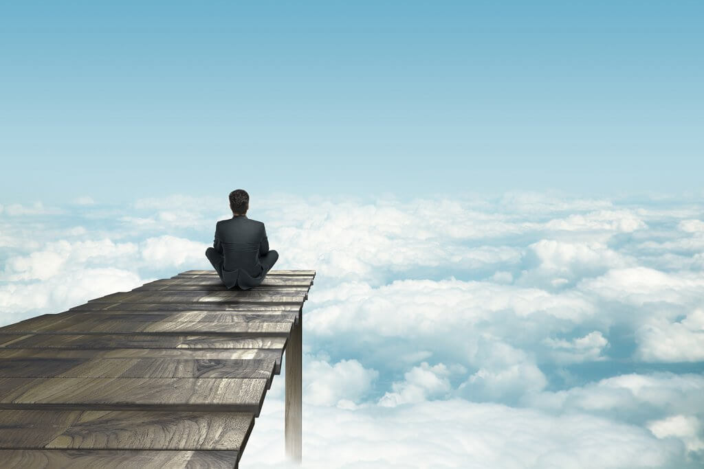 businessman sitting on pier an looking clouds